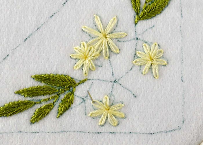 Piccole margherite ricamate con filo giallo chiaro
